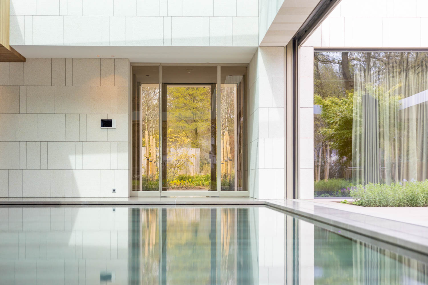 Luxe beige stalen buitendeuren met glas, grenzend aan een moderne villa met zwembad.